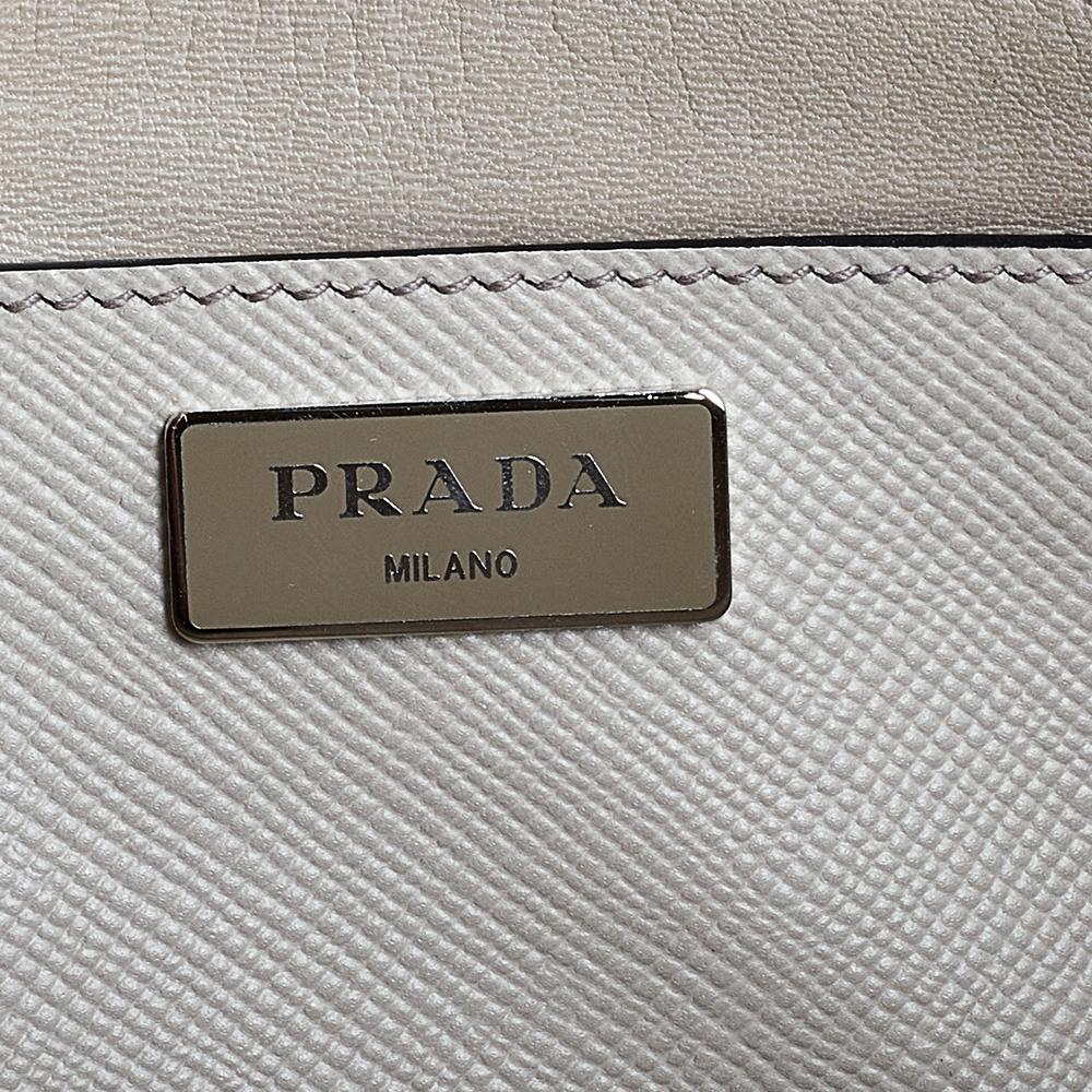 Stay on top of your fashion game with this Twin tote from Prada! Crafted from Saffiano Cuir leather, the tote has a soft hue, two rolled handles, a leather tag, and protective metal feet. The insides are lined and sized to dutifully carry your