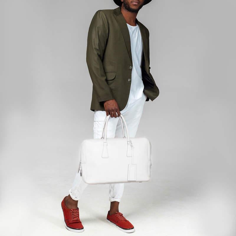Questa elegante borsa Bauletto di Prada è realizzata in pelle saffiano ed è perfetta per il lavoro o per i viaggi. Presenta due manici superiori con finiture in argento e un interno foderato in nylon.