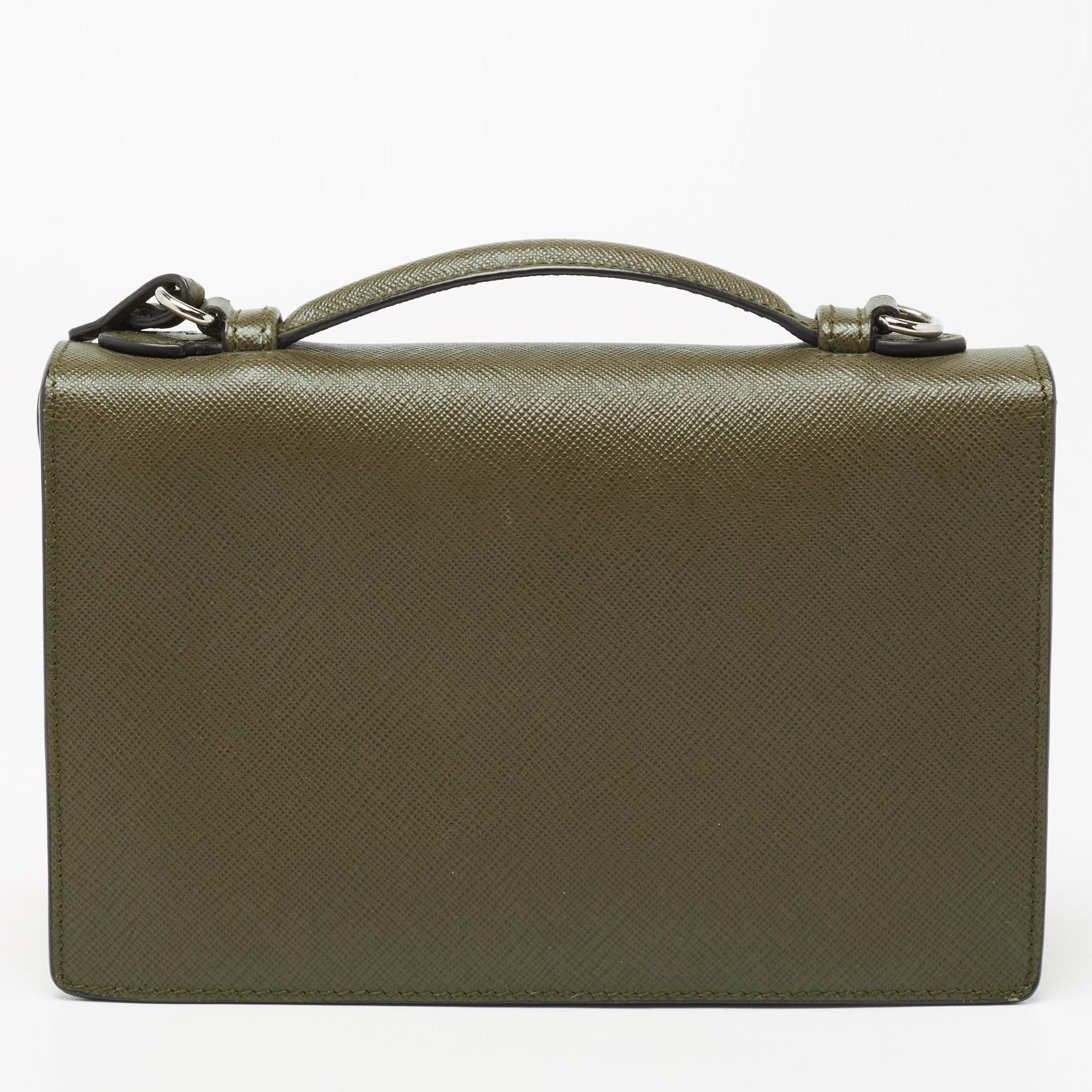 This mini Sound bag from Prada is a style you'll love having in your collection. Crafted with olive green Saffiano Lux leather, it features a structured silhouette with a front flap secured by a silver-tone metal lock. The bag comes with a