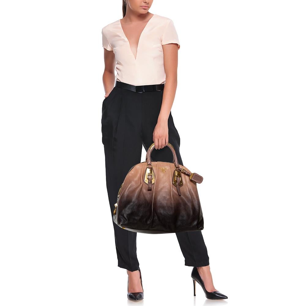 High in appeal and style, this satchel is a Prada creation. It has been crafted from black and beige ombre leather and shaped to exude class and luxury. The bag is adorned with gold-tone buckles and comes with two handles and a spacious interior for