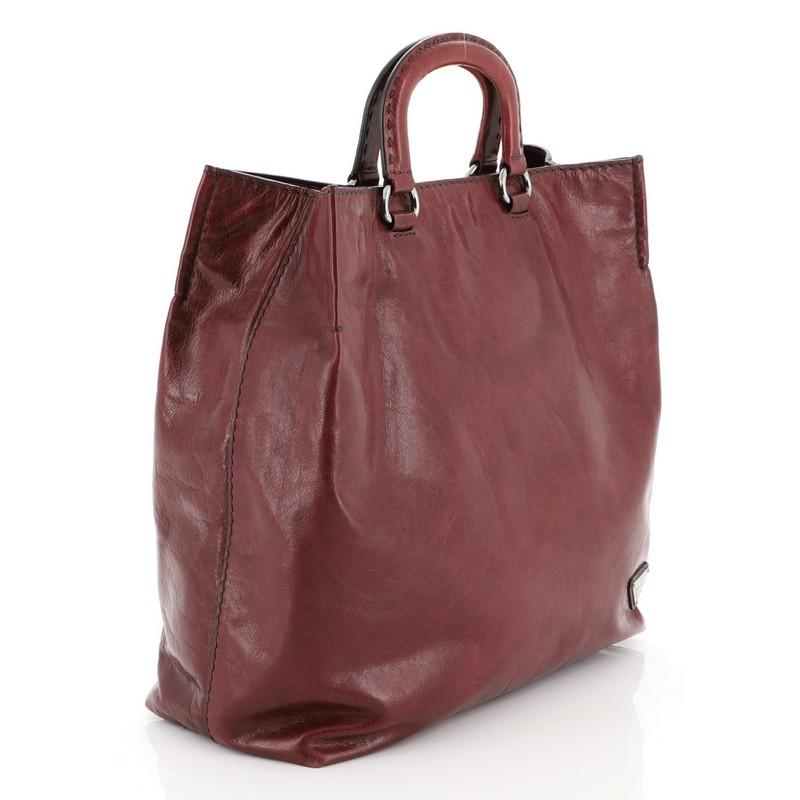 This Prada Open Tote Glace Calf Tall, crafted from red glace calf leather, features dual sturdy handles, Prada logo, and gunmetal-tone hardware. It opens to a red fabric interior.

Estimated Retail Price: $2,400
Condition: Good. Heavy wear on base