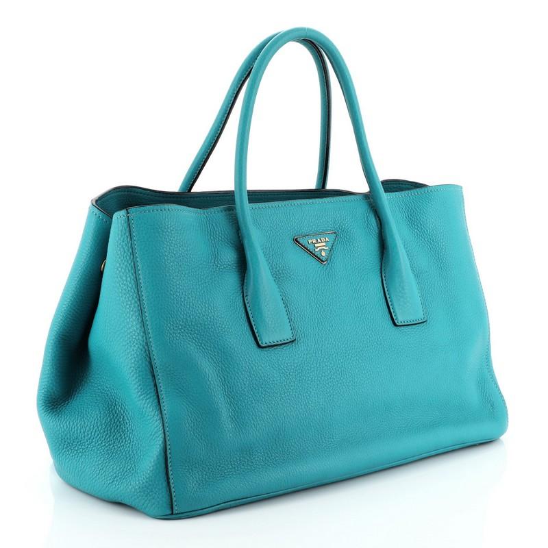 This Prada Open Tote Vitello Daino Medium, crafted in blue vitello daino leather, features dual leather handles and gold-tone hardware. Its opens to a black fabric leather interior with slip pocket. 

Estimated Retail Price: $1,770
Condition: Great.