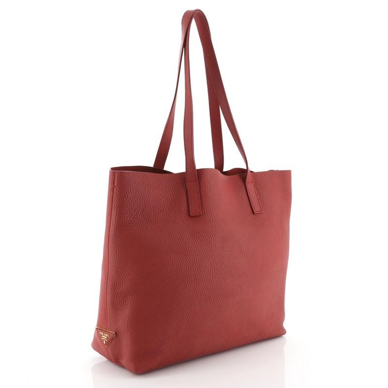 This Prada Open Tote Vitello Daino Medium, crafted in red vitello daino leather, features dual leather handles and gold-tone hardware. Its opens to a red raw leather interior with slip pocket. 

Estimated Retail Price: $1,550
Condition: Very good.