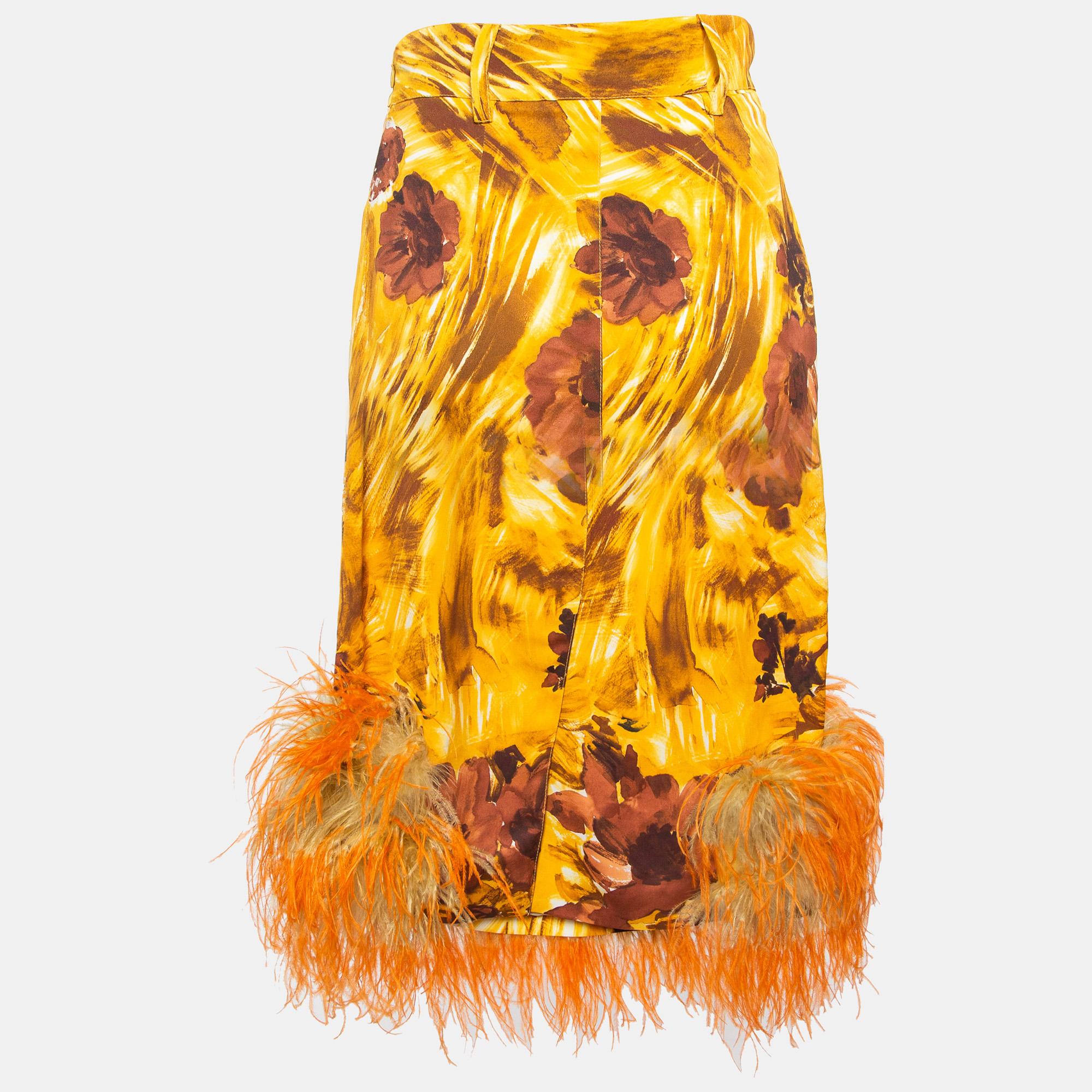 Meticulously crafted and with an enduring appeal,  this Prada skirt showcases the brand's expertise in visionary designs. It is enhanced with the floral detailing and the feather trim at the hem. 