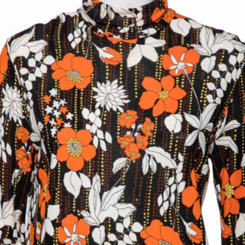 Make a classy style statement by wearing this chic top from the House of Prada. It is tailored using orange printed jersey fabric. It has a zip-type fastening, a turtleneck style, and long sleeves. This top can be complemented with a pair of black