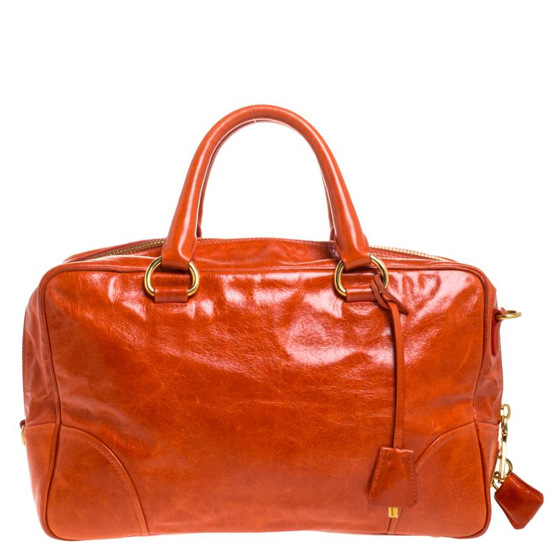 Crafted from orange glazed leather, this handbag features Prada's iconic logo, top zip closure and silver-tone hardware. This bag is accentuated with dual top handles along with a detachable and adjustable shoulder strap and leather clochette to the