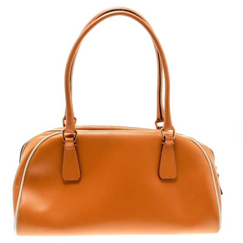 This Bowler bag from Prada is simple in design but highly functional. Crafted from orange leather, the bag features two handles, gold-tone hardware and a top zipper leading to a canvas interior for your necessities. The bag will be a luxe addition