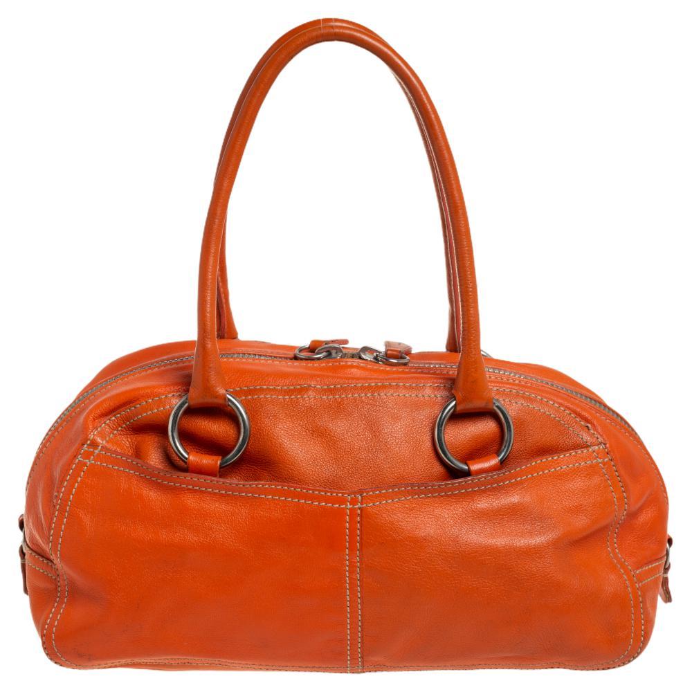 Highly durable and extremely fashionable, this bag comes from Prada. Crafted from orange leather, this bag is styled with a shoulder strap, two exterior pockets, and silver-tone hardware. The interior comes with a pocket and enough space for