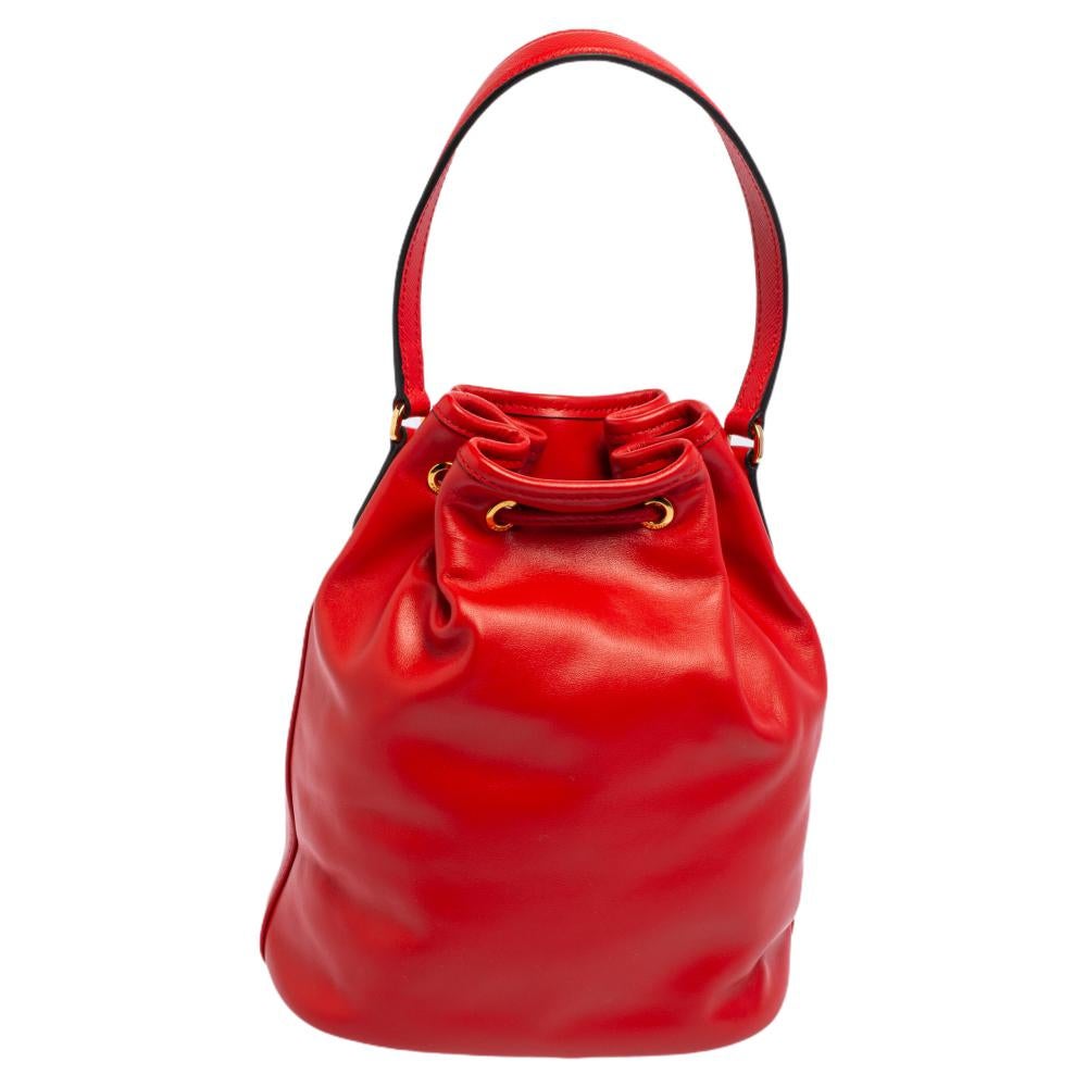 A modern classic, this bucket bag from Prada brings a joyful amalgamation of fashion and functionality. Its bucket shape is rendered in leather featuring the brand label on the front zip pocket, a drawstring fastening, a top handle, and a roomy