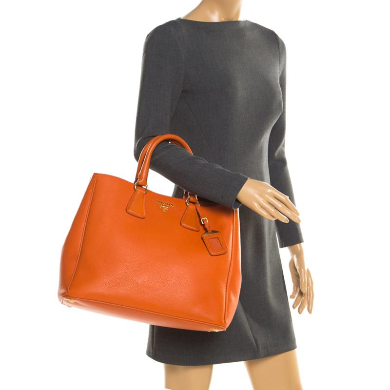 Masterfully crafted with orange leather, this bag will make a memorable addition. Finely lined with fabric, this is a one-stop fashion adornment for all your needs! This Prada bag is splendid for everyday use, and for special events. It is held by