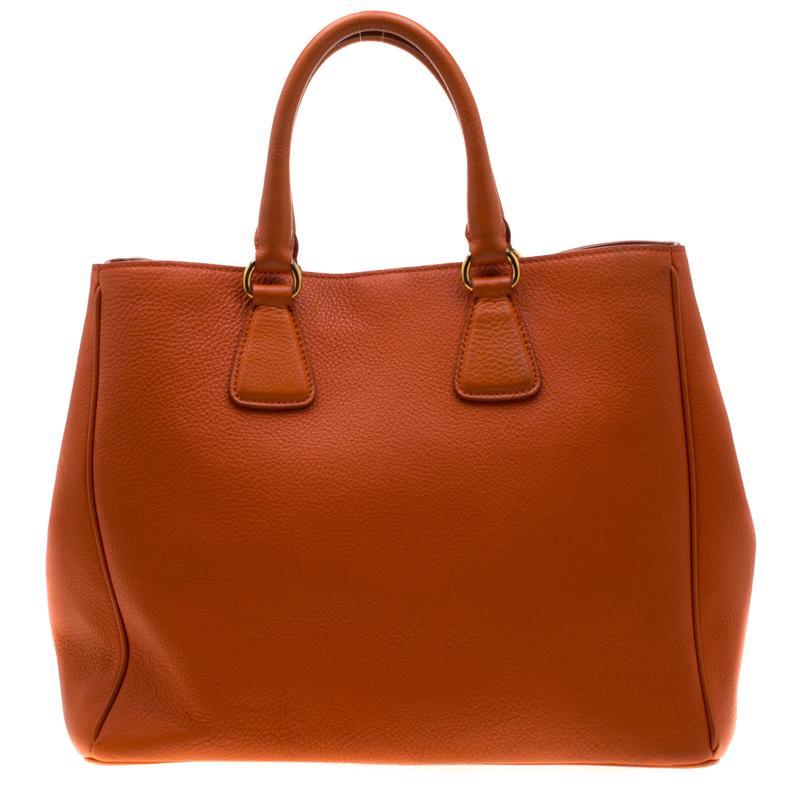 Masterfully crafted with orange leather, this bag will make a memorable addition. Finely lined with fabric, this is a one-stop fashion adornment for all your needs! This Prada bag is splendid for everyday use, and for special events. It is held by