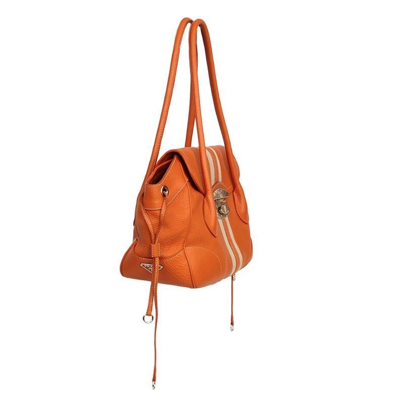 Prada shoulder bag in orange leather with details in canvas and beige lizard skin. Closes with push-lock on the front. Lined in orange monogram nylon with a zipper pocket against the back. Has been carried and is in excellent condition. Very minimal