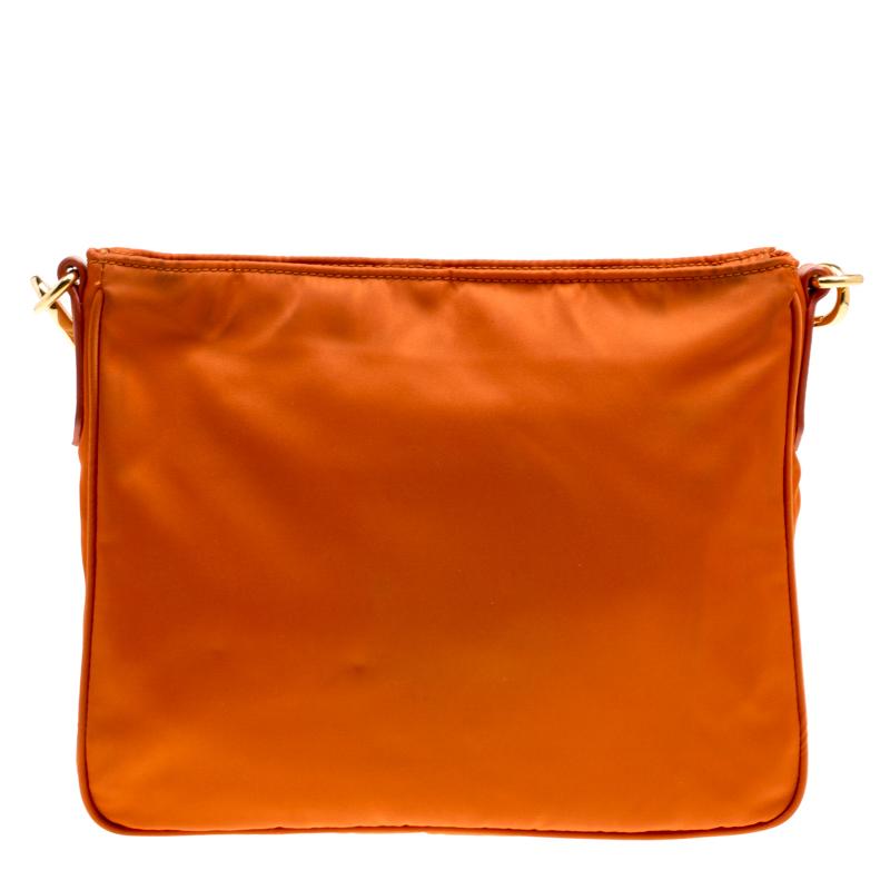 This stylish Prada bag in gorgeous orange hue is made of durable nylon with leather trims and gold-tone hardware. The matching nylon-lined interior has a zippered wall pocket. The bag has a zip closure and an external zip pocket. The adjustable