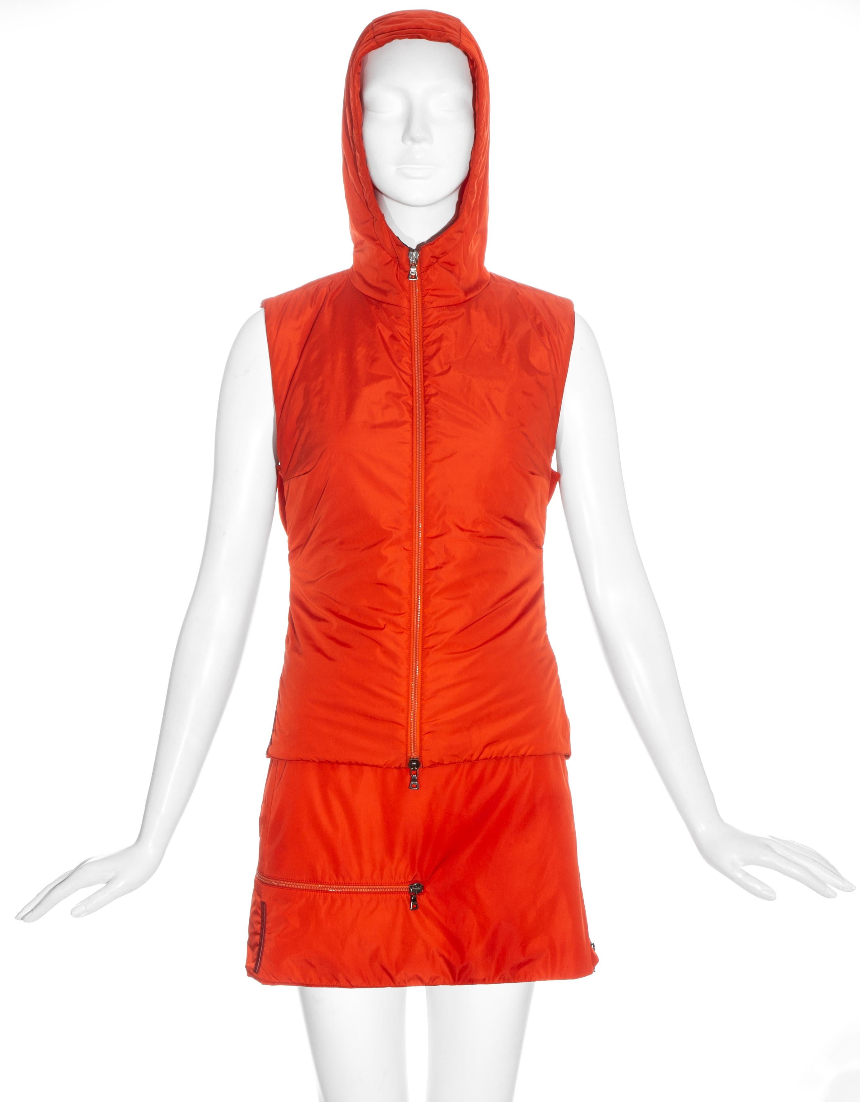 Ensemble Prada en nylon orange comprenant : gillet zippé à capuche avec panneau arrière en laine noire et deux fermetures élastiques ; mini-jupe zippée avec deux poches 

c. 1999