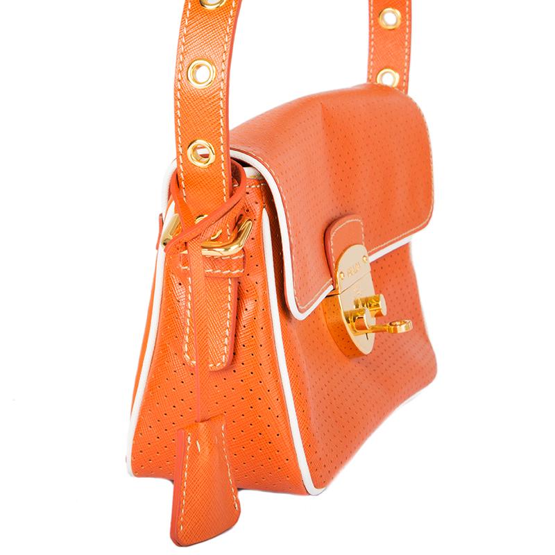Prada baguette shoulder bag in orange perforated Saffiano leather with white trim. Closes with a lock on the front. Lined in orange logo nylon with a zipper pocket against the back. Has been carried and is in excellent condition.

Height 14.5cm