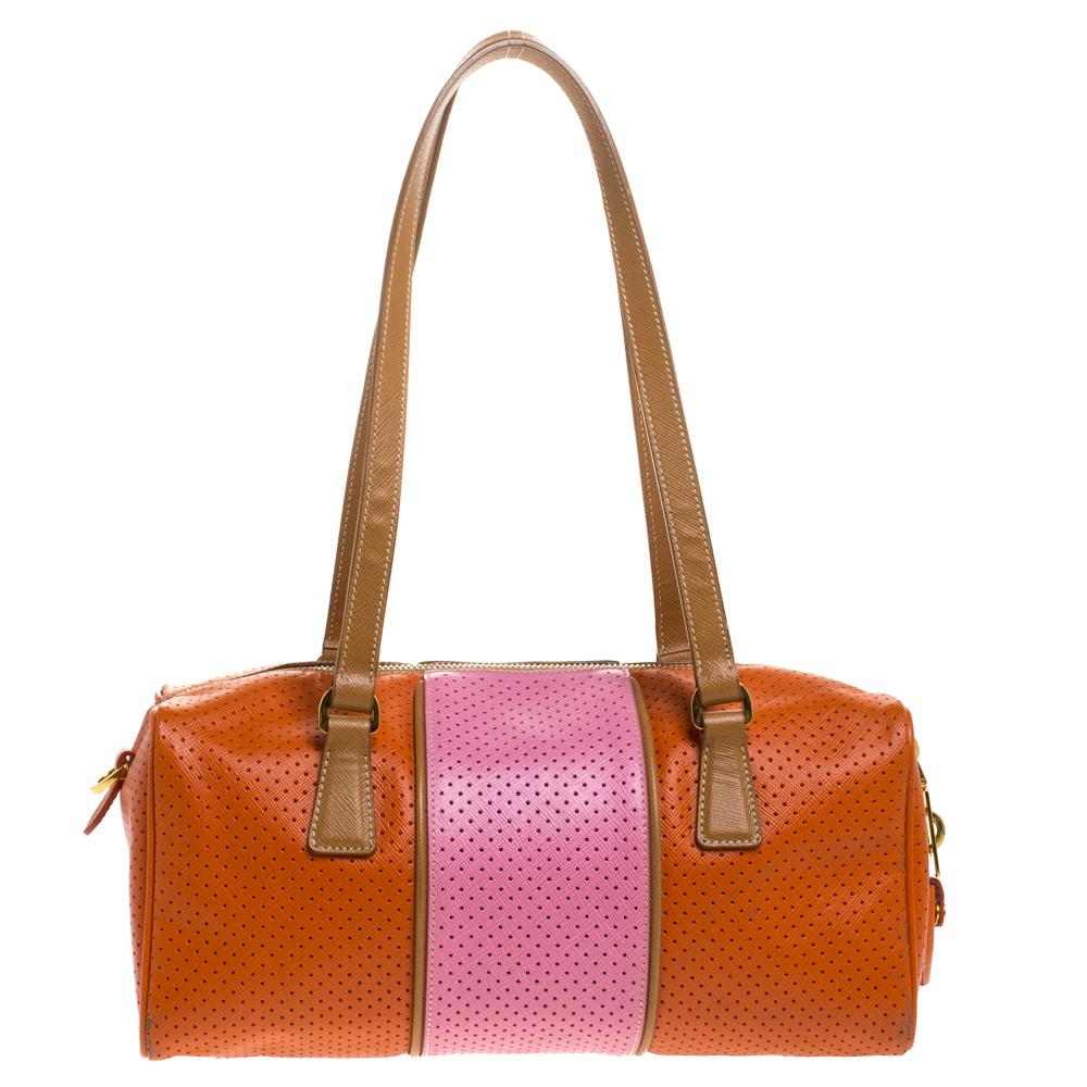 Ideal for travel or weekends, this Prada Boston bag is stylish and spacious. It is crafted in orange-pink perforated leather carrying a striped design and comes with two top handles. It is secured with a top zipper closure and opens to reveal a