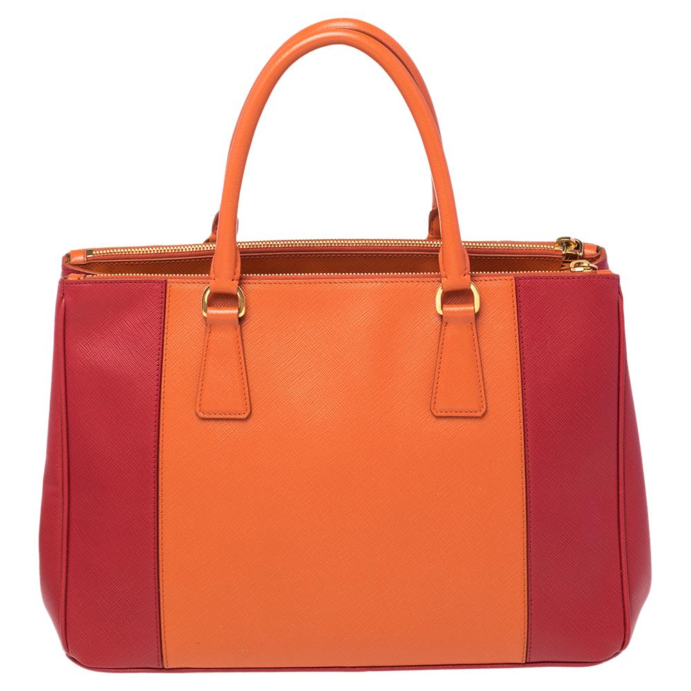Loved for its classic appeal and functional design, Galleria is one of the most iconic and popular bags from the house of Prada. This beauty in red and orange is crafted from Saffiano Lux leather and is equipped with two top handles, the brand logo
