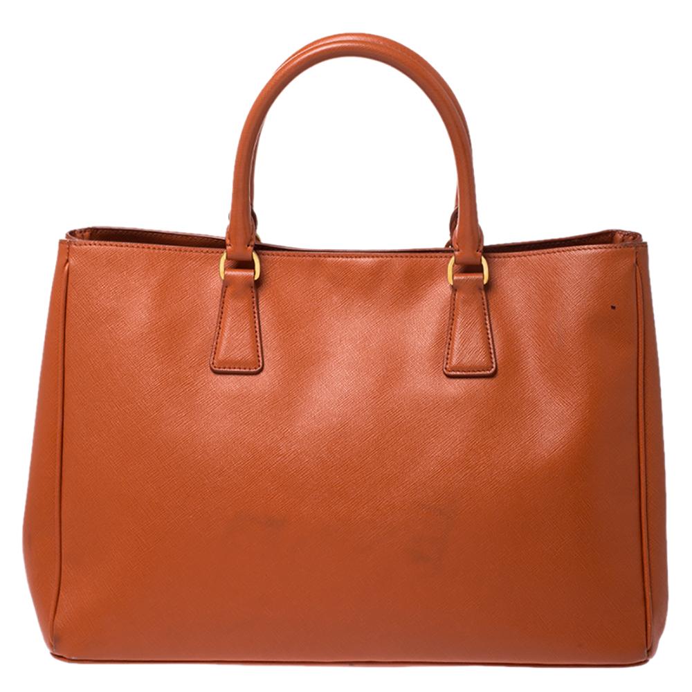 High in appeal and style, this tote is a Prada creation. It has been crafted from leather and shaped to exude class and luxury. The bag comes with two handles and a spacious nylon interior for your ease. Protective metal feet and the brand logo on