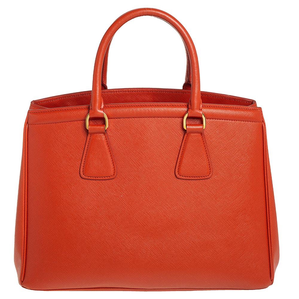 Classic and refined with a modern edge, this tote stands out with its well-defined shape. It is crafted from Saffiano Lux leather and boasts dual top handles. Equipped with protective metal feet, it opens to a nylon-lined interior that lends support