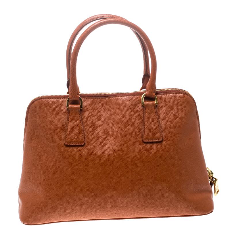 This stunning Promenade tote is high on appeal and style. Dazzling in a classy orange shade, it is crafted from Saffiano Lux leather and features two rolled handles and a name tag. The top zipper leads way to a nylon-lined interior with enough space