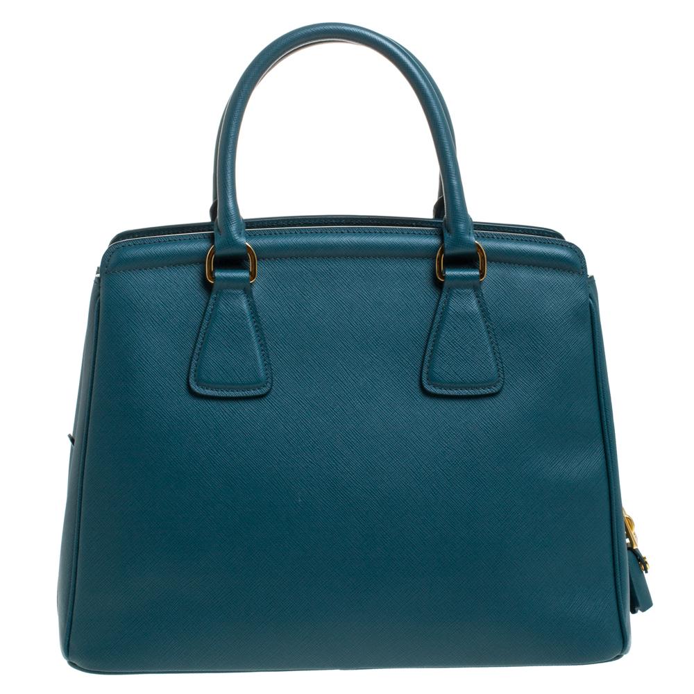 Masterfully created, this Prada Parabole tote is a style icon. Designed in a Saffiano Lux leather body, it exudes style and class in equal measures. This delightful blue piece is held by two top handles and equipped with a spacious nylon