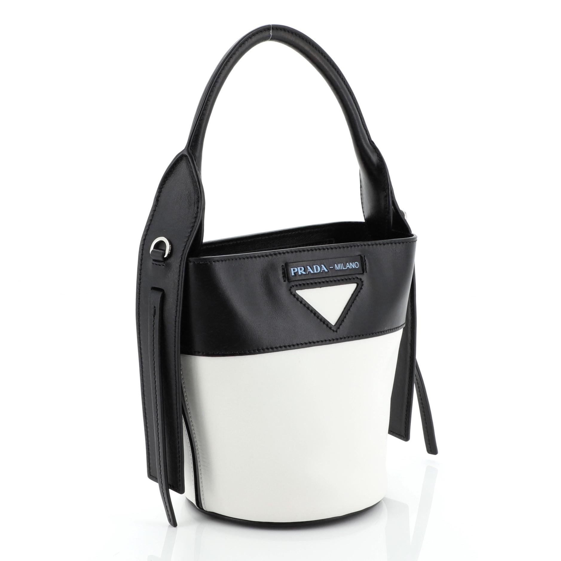 This Prada Ouverture Bucket Bag Leather, crafted from white and black leather, features rolled top handle and silver-tone hardware. Its zip closure opens to a black leather interior. 

Estimated Retail Price: $1,330
Condition: Great. Scuffs and