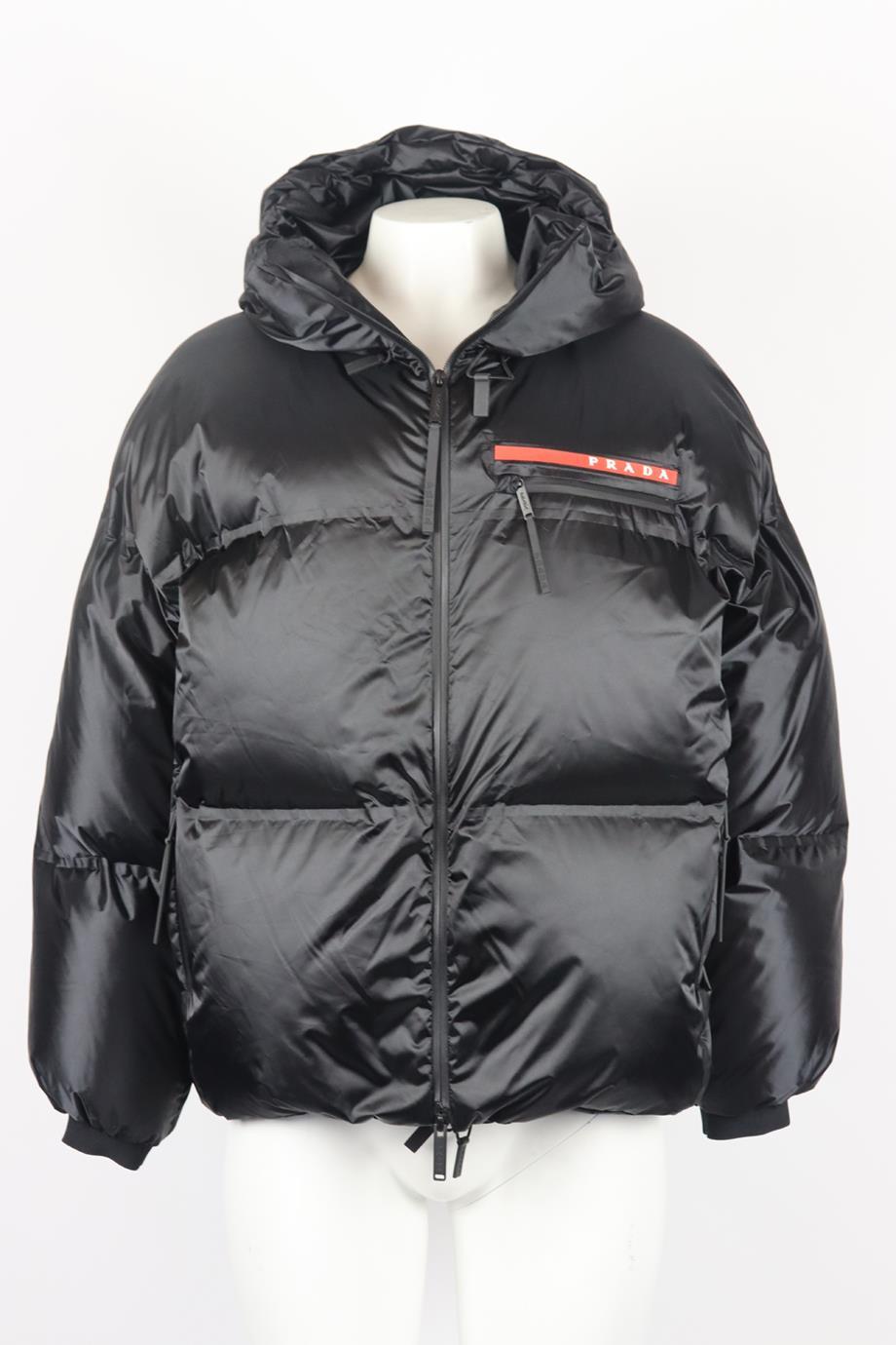 Prada oversized hooded quilted shell down jacket. Black. Long sleeve, crewneck. Zip fastening at front. Comes with suit carrier. Size: XSmall (UK 6, US 2, FR 34, IT 38). Shoulder to shoulder: 22.5 in. Bust: 56 in. Waist: 53 in. Hips: 48 in. Length: