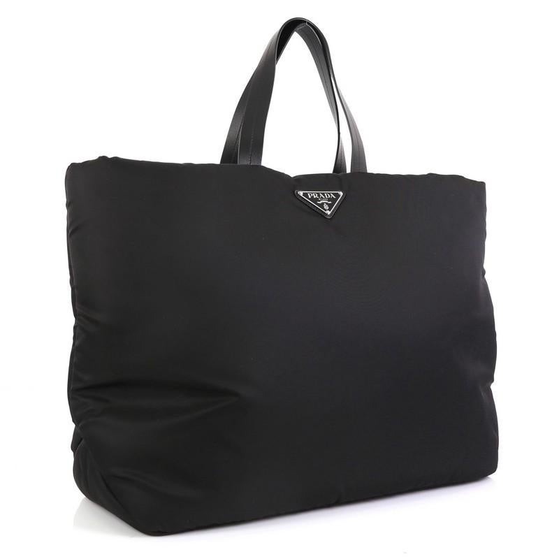 This Prada Padded Tote Tessuto Medium, crafted from black tessuto, features dual flat leather handles, triangle Prada logo, and silver-tone hardware. Its zip closure opens to a black nylon interior with side zip pocket. 

Estimated Retail Price: