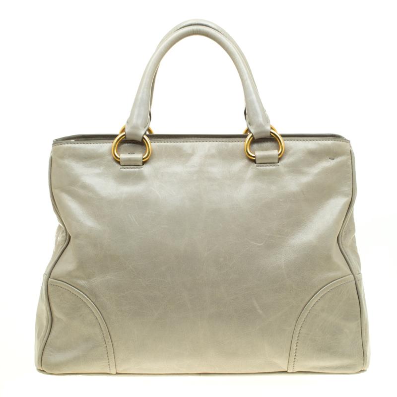 This pale green bag from Prada is very chic and stylish. It is crafted from glazed leather and radiates a shine making it look amazing. It features dual top handles with an attached tag accent, gold-tone brand logo at the front and protective metal