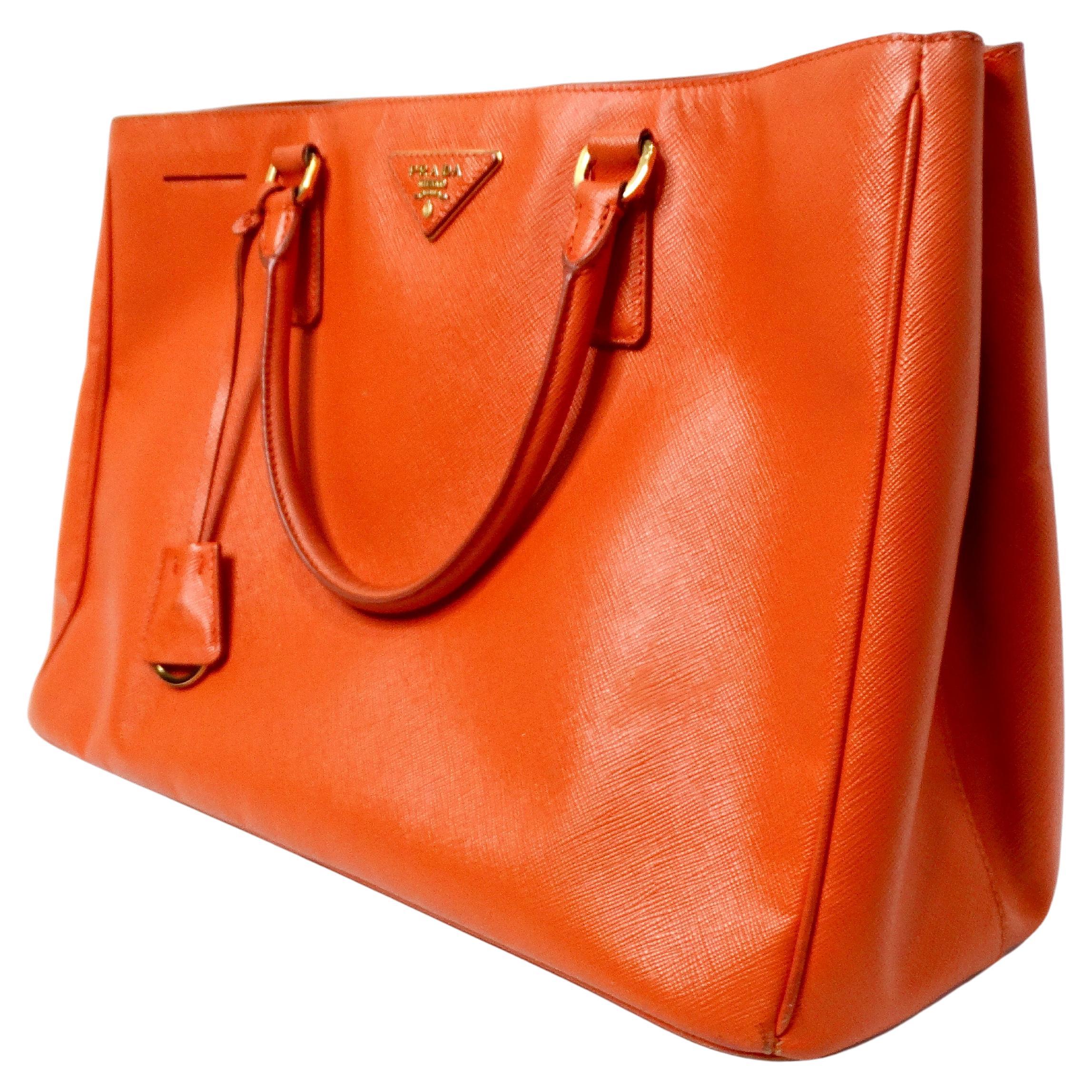 The Prada Papaya Saffiano Leather Lux Galleria Tote Bag is a sophisticated and versatile accessory that epitomizes timeless elegance and modern luxury. Crafted from signature saffiano leather, it offers durability and a refined texture, while the