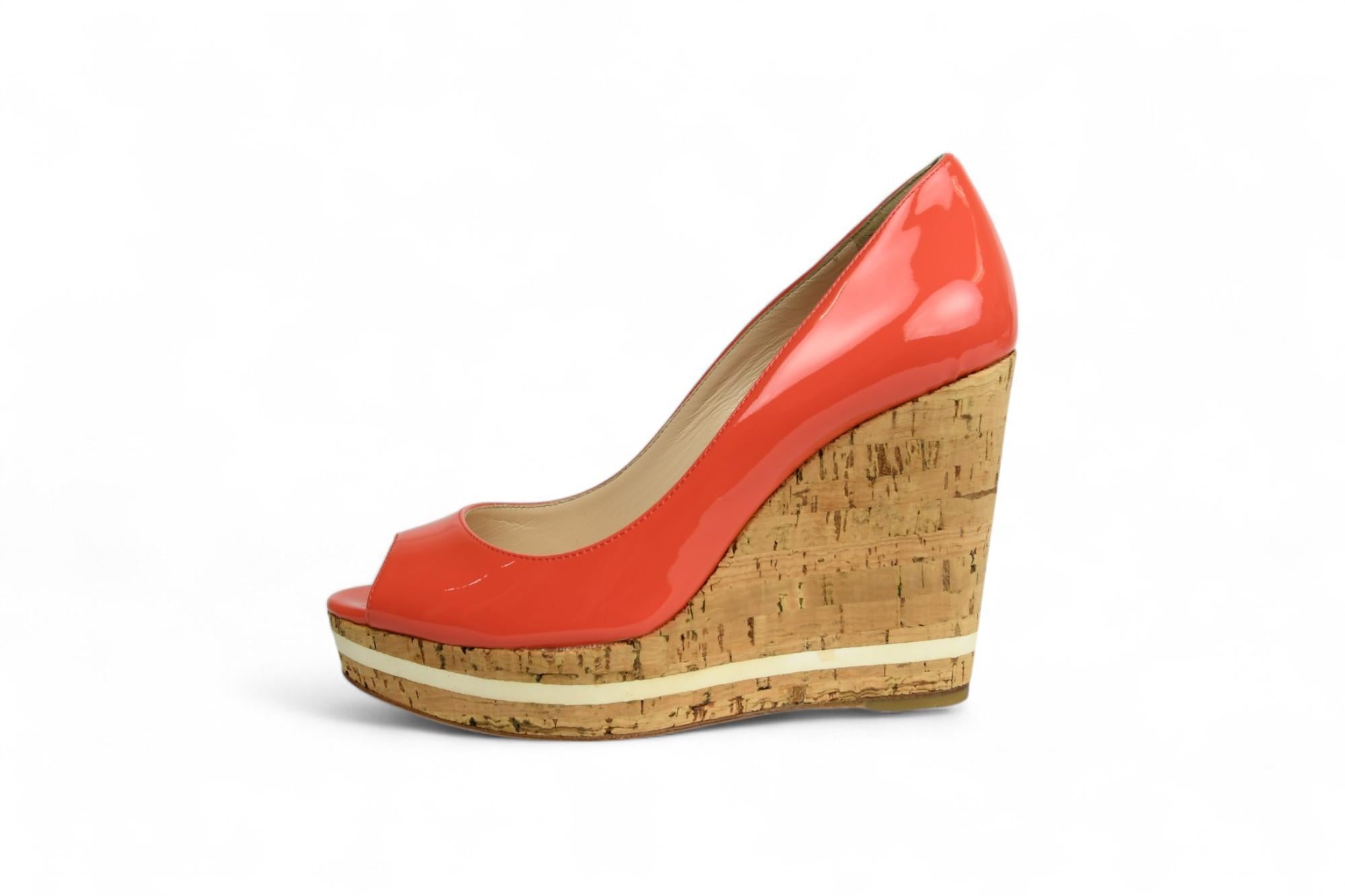 Ravviva il tuo guardaroba per la stagione calda con queste vivaci zeppe di Prada, realizzate in vernice corallo con suola in sughero naturale. La silhouette peep toe e la tomaia lucida offrono un'atmosfera giocosa ma raffinata, mentre la zeppa in