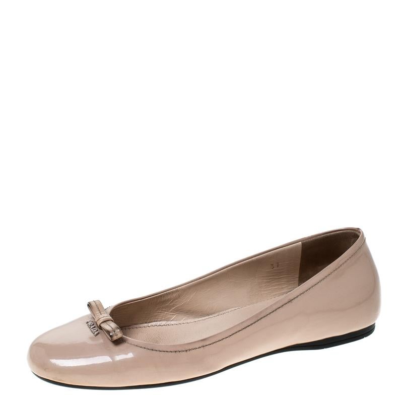 Minimalistic yet fashionable, these ballet flats from Prada are perfect for everyday wear. These beige flats are crafted from patent leather and feature round toes with brand logo and bows detailed on the vamps. They come equipped with leather-lined