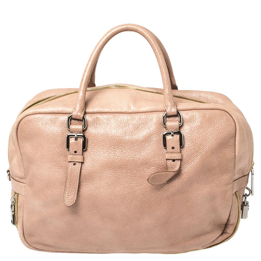 This lovely bag from Prada is crafted from pink Cervo Lux leather. It flaunts dual top handles, a brand logo on the front, buckle details, and an interior with enough space to house all your belongings. It is finished with gold-tone hardware and