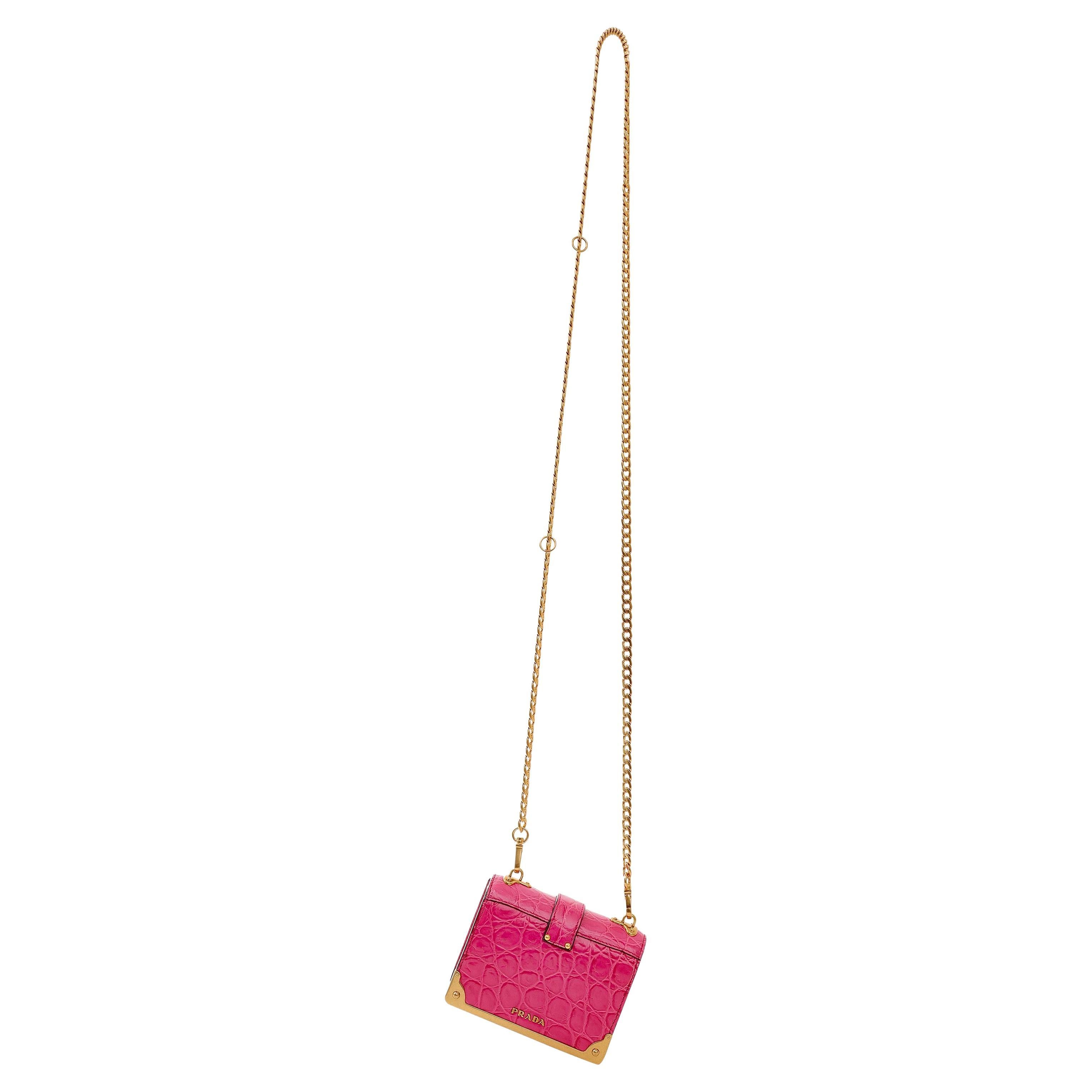 Cet authentique sac Micro Cahier en crocodile rose de Prada est en parfait état.  Crocodile rose vif et quincaillerie dorée.  Longue chaîne en métal doré. Sac à poussière inclus.

PBF 13769
