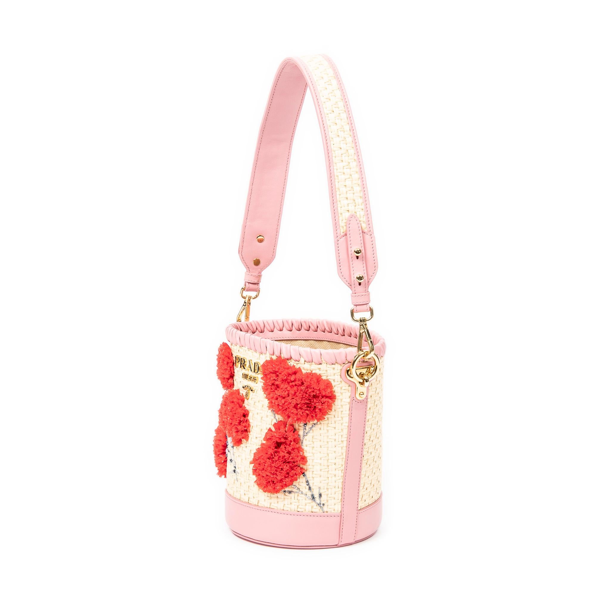 Prada’s Pink Embroidered Raffia Bucket Bag is casually elegant with its gold hardware and open top, leading to a spacious woven canvas interior with a single zippered pocket.

SPECIFICS
Length: 8