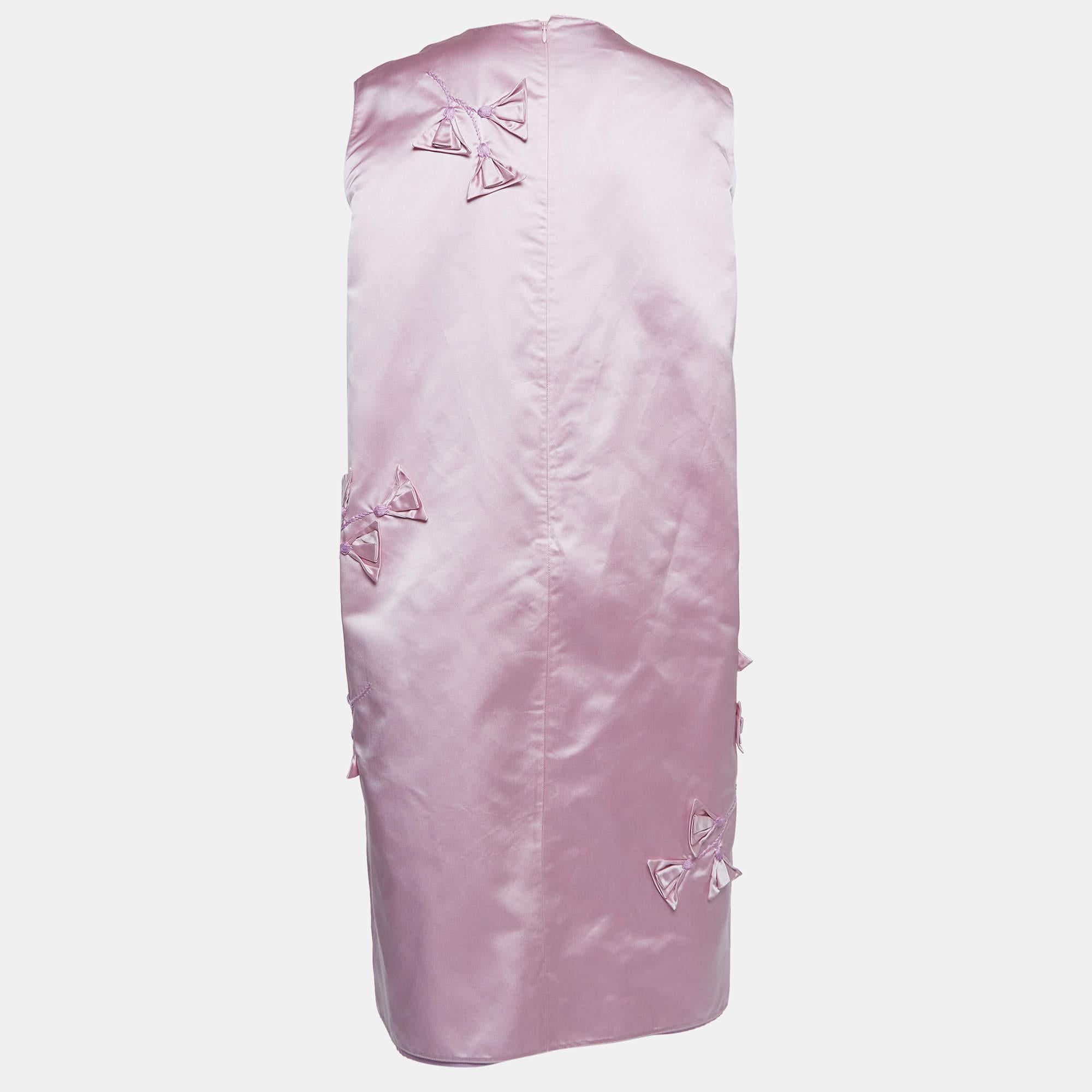 The Prada dress is a stunning piece featuring intricate floral appliques on luxurious silk fabric. With a duchess shift silhouette, it exudes elegance and modernity, making it a sophisticated choice for special occasions with its vibrant pink hue