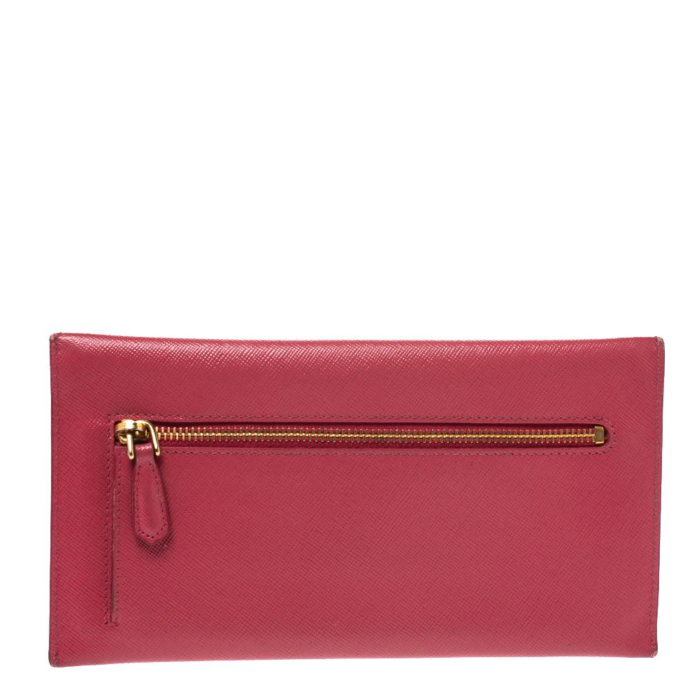 Finely crafted and high in appeal is this envelope wallet by Prada. It has been crafted from pink Saffiano leather and shaped beautifully. The clutch has a flap with gold-tone logo accents and it secures the leather & fabric interior for your little