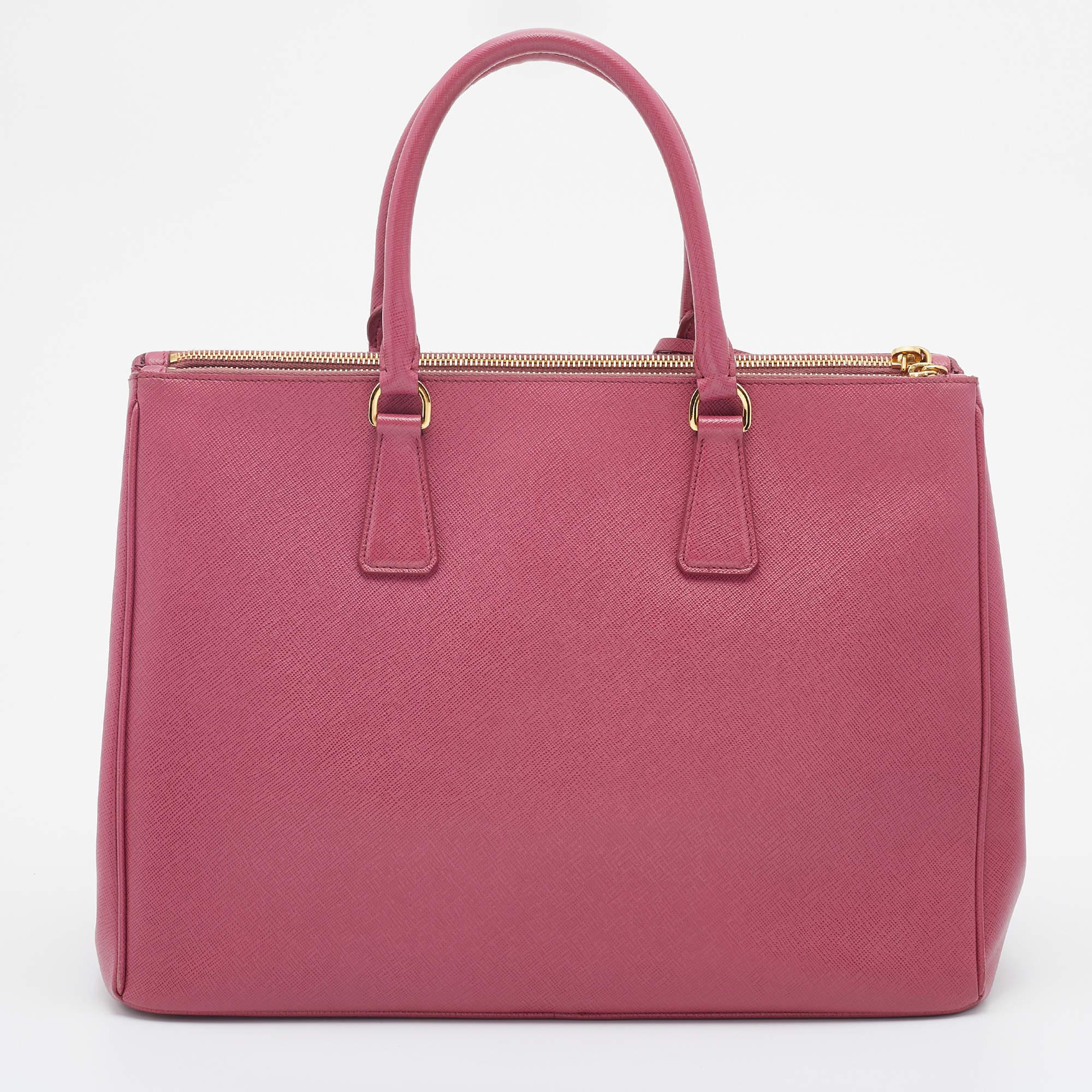 Feminine in shape and grand in design, this Double Zip tote by Prada will be a valuable addition to your closet. It has been crafted from Saffiano leather and styled minimally with gold-tone hardware. It comes with dual handles at the top, two zip