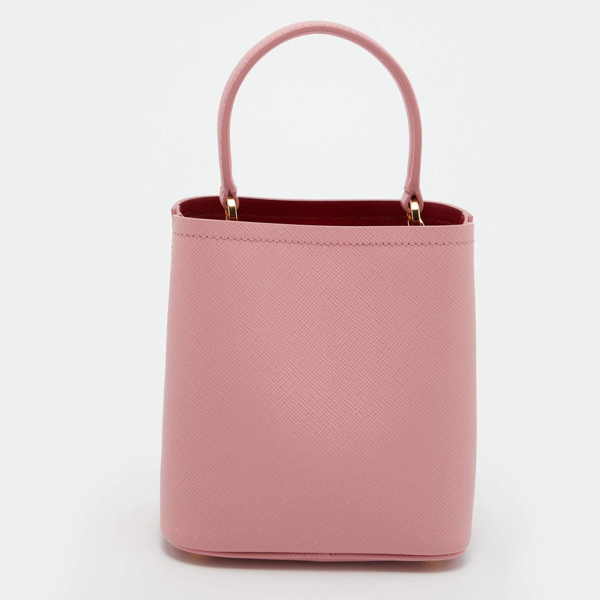 Prada's signature trait of luxury and class is displayed in this bag from the Panier collection. It is a top-handle leather bag that comes with a detachable strap and has the brand's logo fitted on the front in gold-tone metal. This pink-hued bag