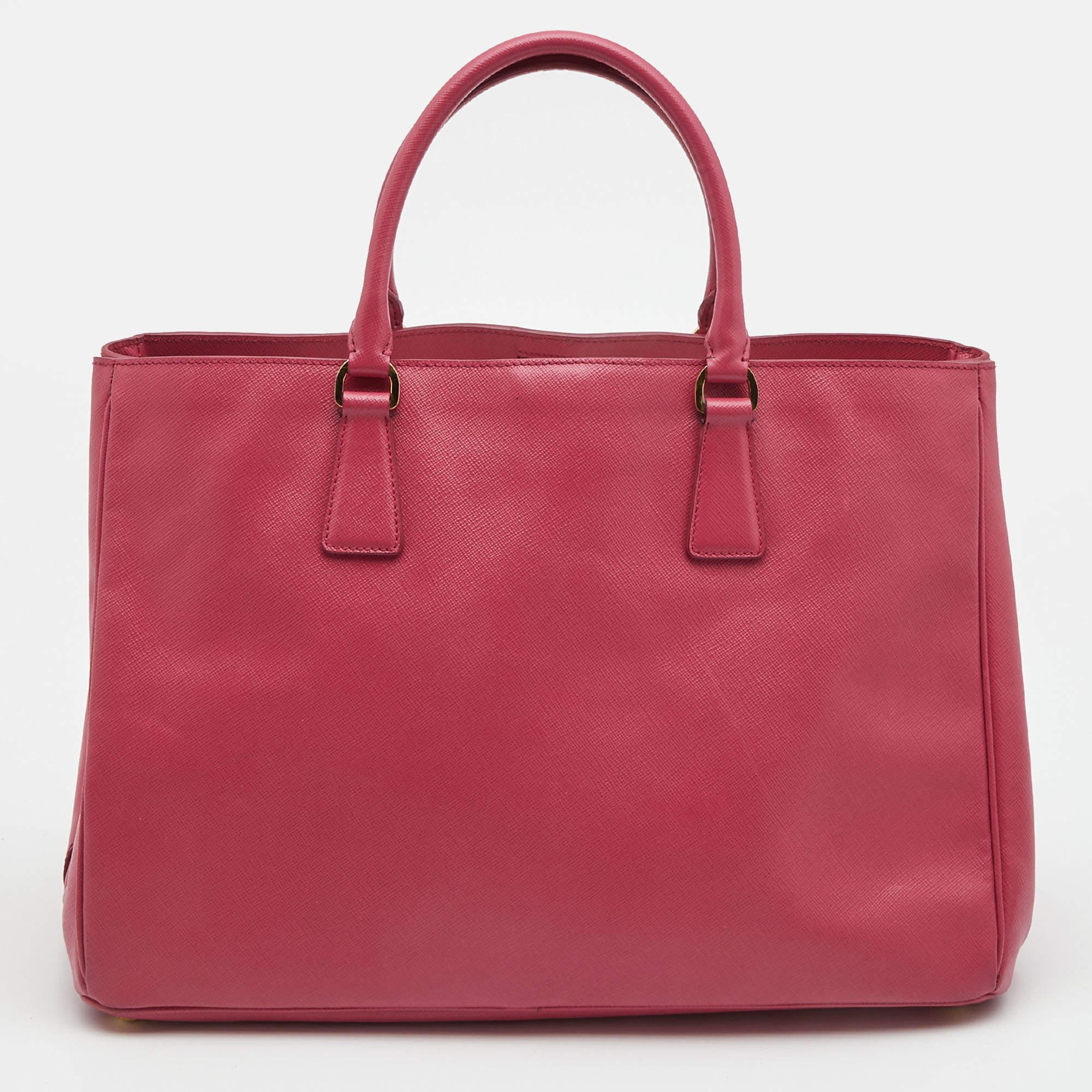 Sophisticated and timeless, this practical Gardener's tote by Prada aims to elevate your daily style. It is crafted from durable Saffiano lux leather in an elegant shade of pink. The bag features a front Prada logo, double handles, a leather-covered