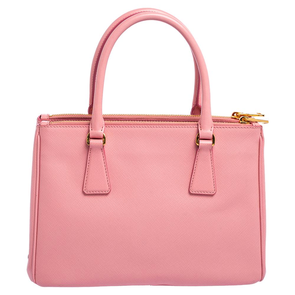 Feminine in shape and grand on design, this Double Zip tote by Prada will be a loved addition to your closet. It has been crafted from Saffiano lux leather and styled minimally with hardware accents. It comes with two top handles, two zip