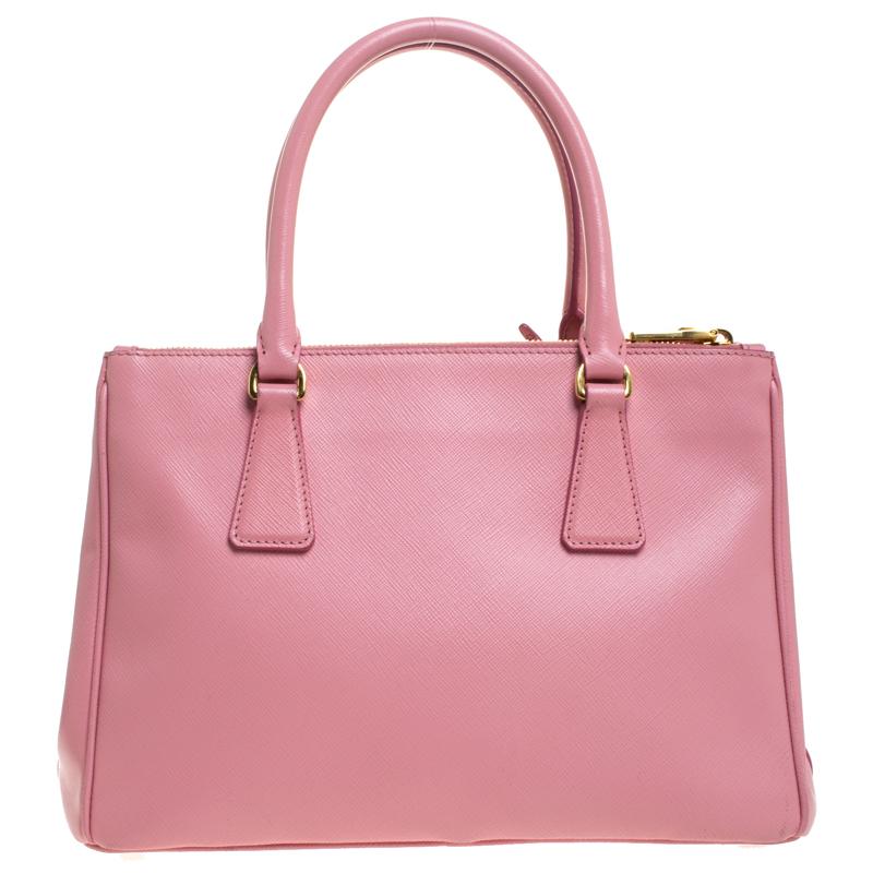 Feminine in shape and grand on design, this Double Zip tote by Prada will be a loved addition to your closet. It has been crafted from Saffiano Lux leather and styled minimally with gold-tone hardware. It comes with two top handles, two zip