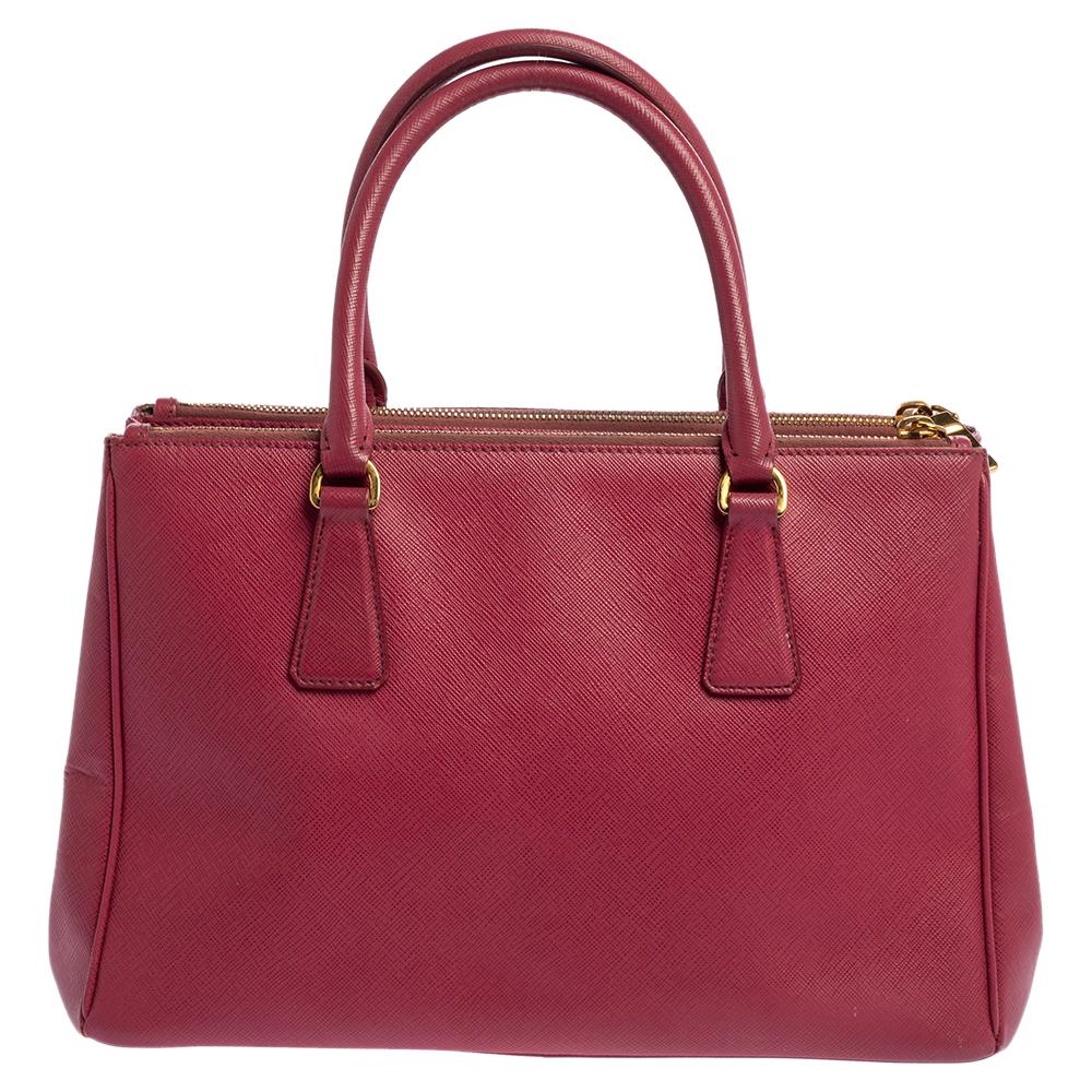 Loved for its classic appeal and functional design, Galleria is one of the most iconic and popular bags from the house of Prada. This beauty in pink is crafted from Saffiano Lux leather and is equipped with two top handles, the brand logo at the