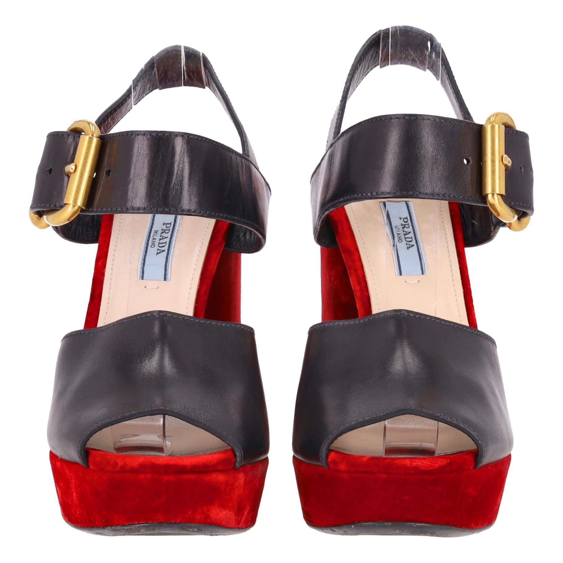 Sandali Prada con plateau in pelle e tacco in velluto

Sandali neri realizzati in pelle liscia nera con ampio cinturino sul davanti e chiusura alla caviglia con fibbie dorate.

Adornate da un plateau in velluto rosso a contrasto e da un tacco a
