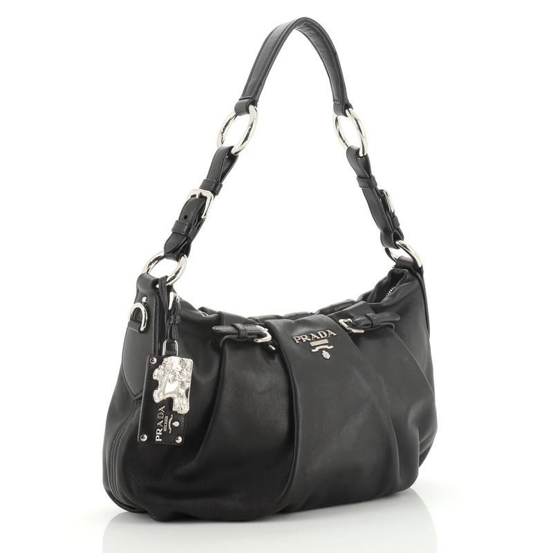 This Prada Pleated Hobo Soft Calfskin Medium is ideal for everyday use. Crafted in black soft calfskin leather, features a flat leather shoulder strap, raised Prada logo and silver-tone hardware. Its magnetic snap closure opens to a black fabric