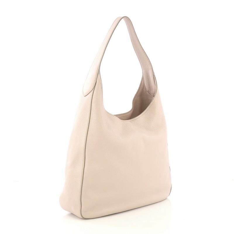 This Prada Pocket Hobo Vitello Daino Medium, crafted from pale pink vitello daino leather, features a looping handle, exterior slip pocket, and silver-tone hardware. It opens to a beige fabric interior with zip and slip pockets. 

Estimated Retail