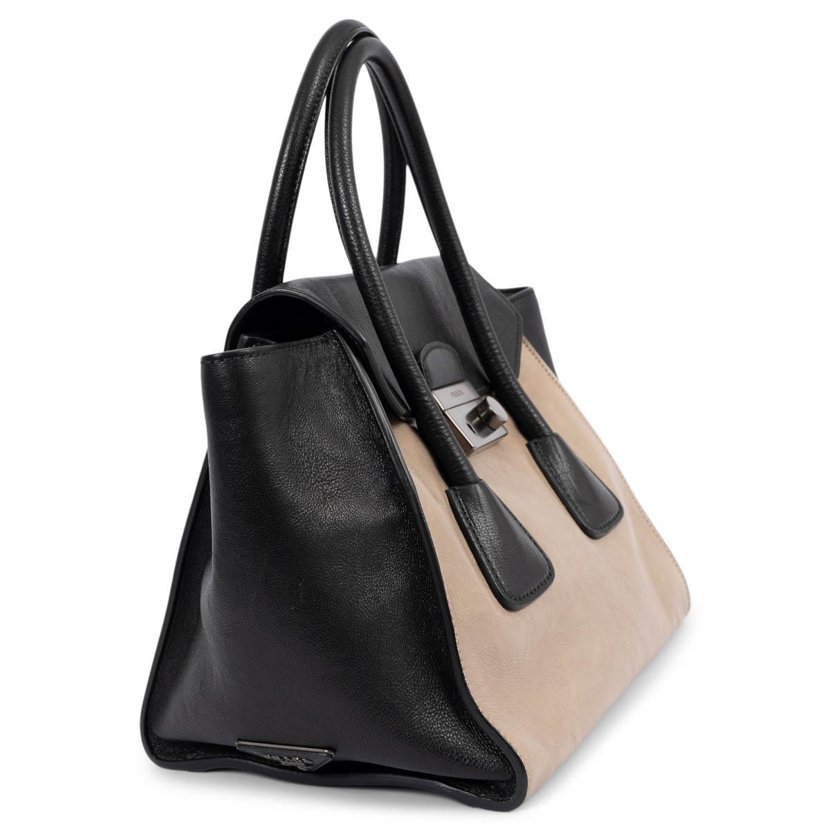 100% authentic Prada Sound tote in black and pomice beige Glace calfskin leather. Features a black detachable and adjustable shoulder strap, a front lock in sateen silver-tone with keys and clochette. Lined in black monogram nylon with an open and