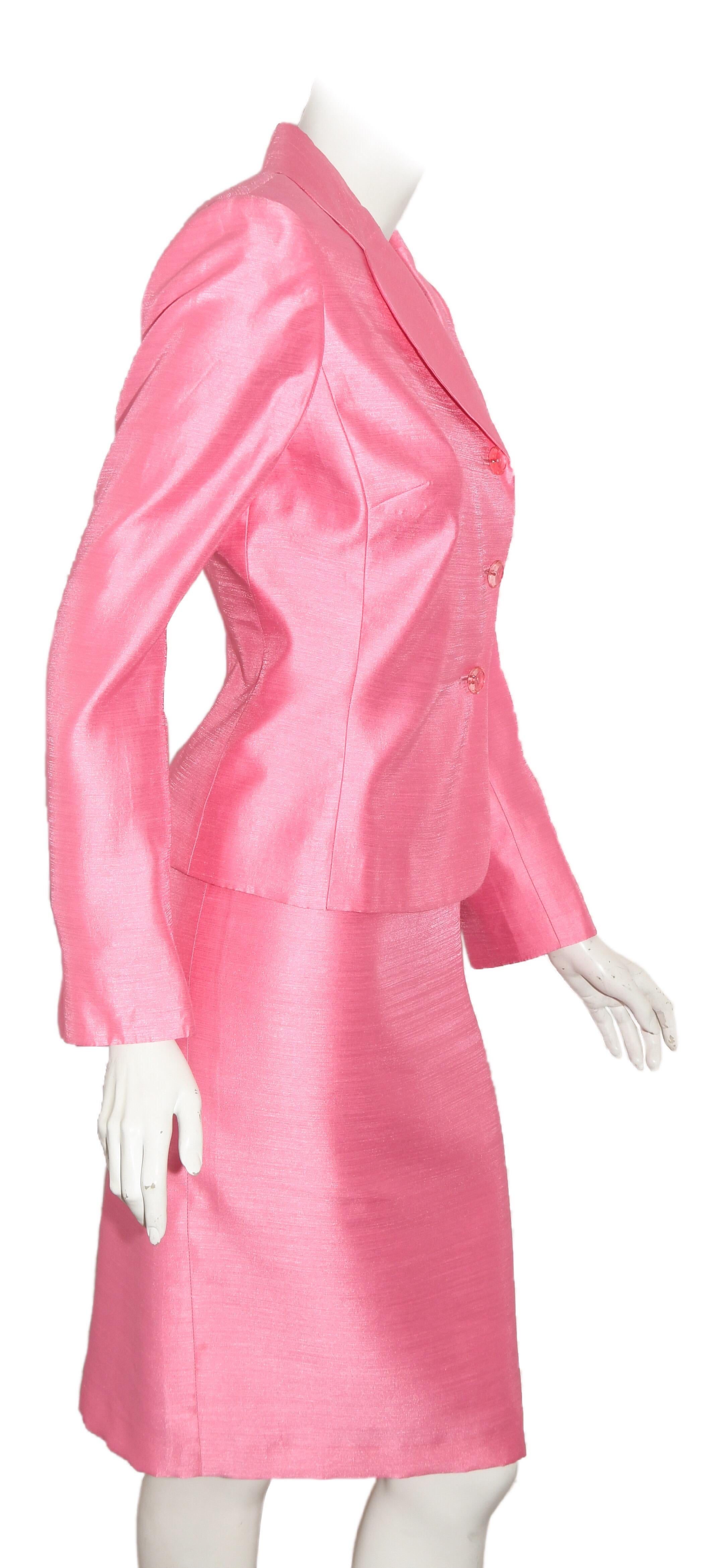 Prada springs forward in this pink skirt suit with rounded notch collar that includes three translucent buttons at front for closure. This suit is fully lined, both the skirt and the jacket, in pink viscose.   The long sleeves have a slit vent at
