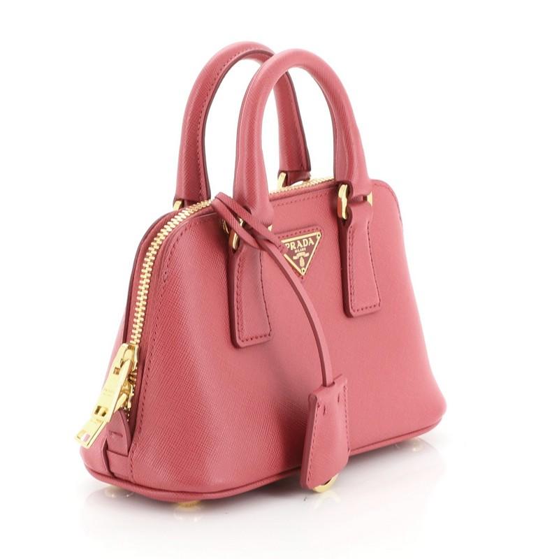 This Prada Promenade Bag Saffiano Leather Mini, crafted from pink saffiano leather, features dual rolled handles, triangle Prada logo, and gold-tone hardware. Its zip closure opens to a pink fabric interior with slip pocket. 

Estimated Retail