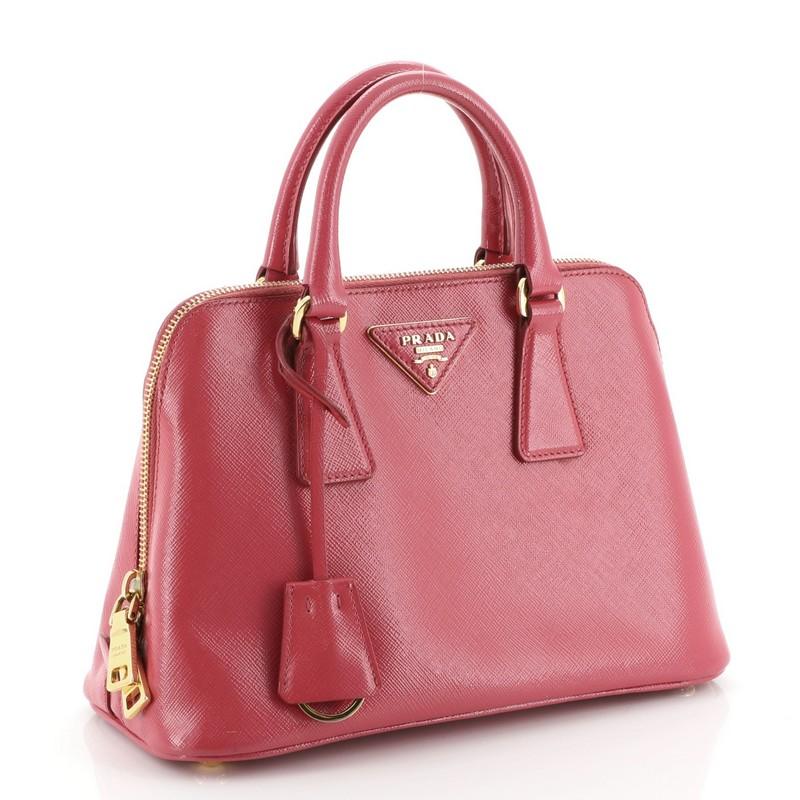 This Prada Promenade Bag Vernice Saffiano Leather Small is a perfect everyday bag fit for the modern woman. Crafted from pink vernice saffiano leather, features dual rolled handles, protective base studs and gold-tone hardware. Its zip closure opens